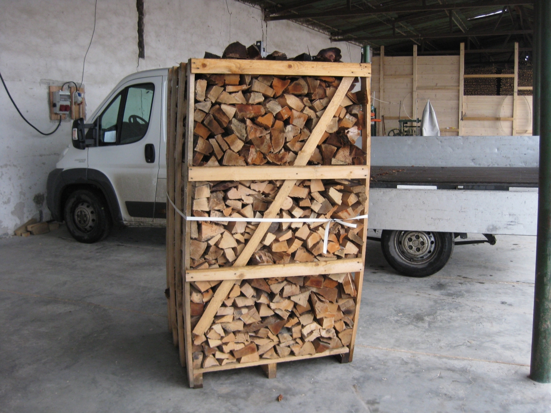A wooden cage filled with firewood and a pickup truck in the back.