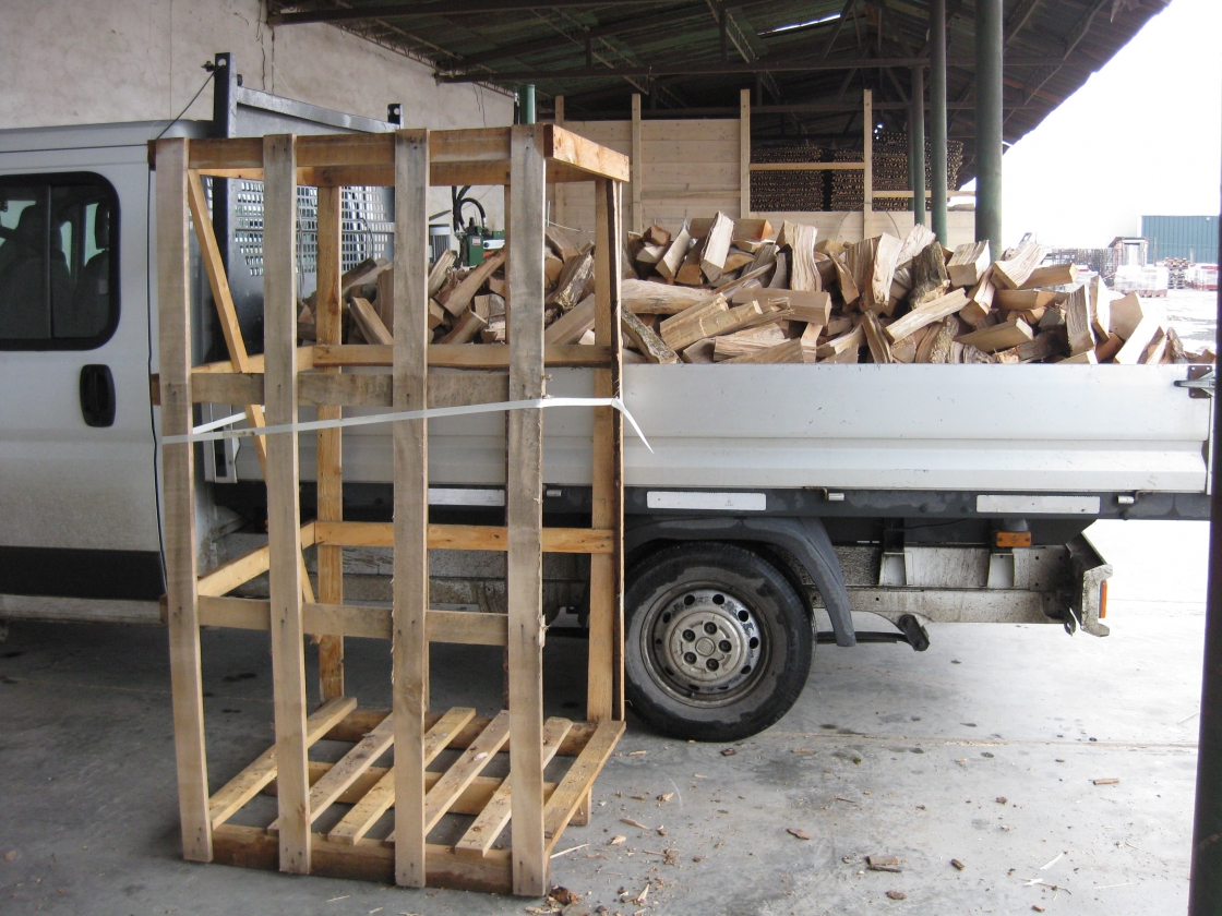Une caisse en bois vide avec, à côté, une camionnette remplie de bois de chauffage.