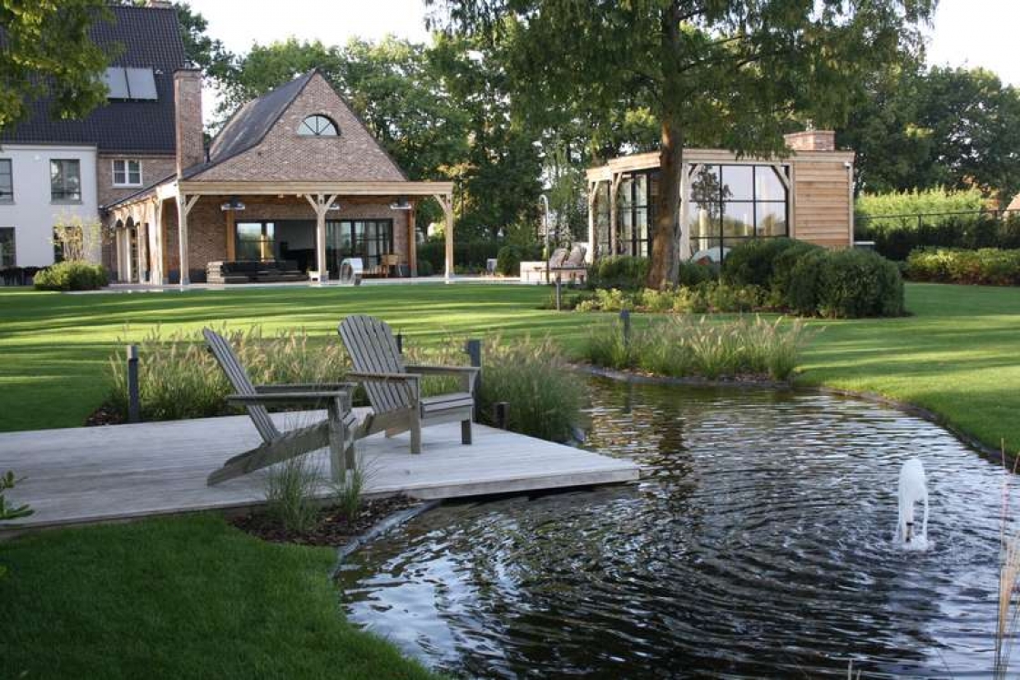 Une plate-forme en bois modifiée thermiquement avec des chaises en bois au bord d'un étang.